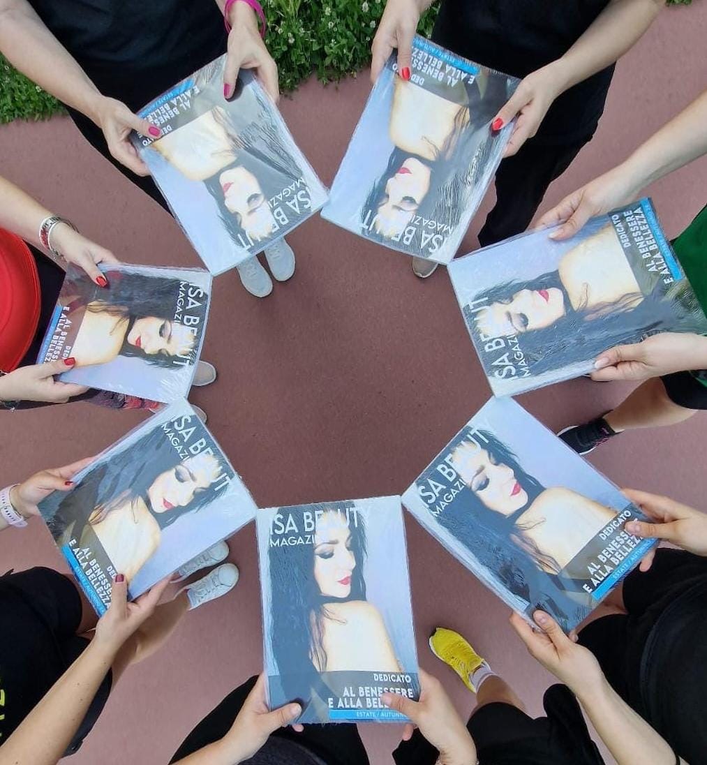 Gruppo di persone che tengono Isa Beauty Magazine in cerchio, rivista dedicata al benessere e alla bellezza